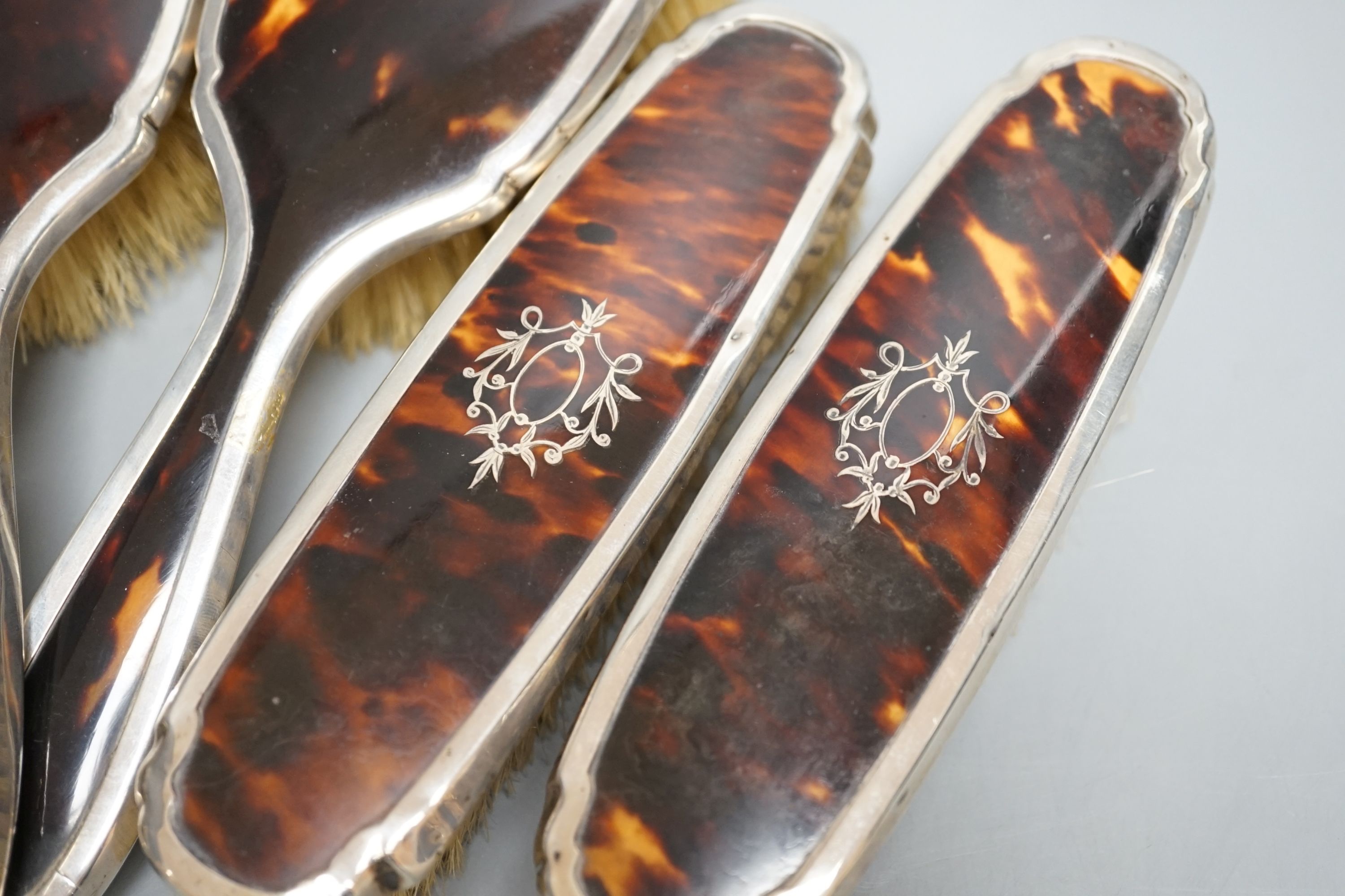 A George V silver and tortoiseshell mounted mirror and brush set, Birmingham, 1928 and a similar powder jar.